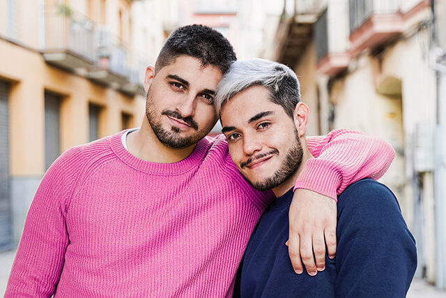 gay-couple-smiling-on-camera-on-city-street-male-2025-02-13-01-05-12-utc (1)